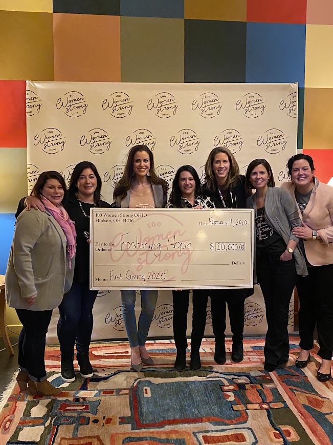 Fostering hope recipients holding large check