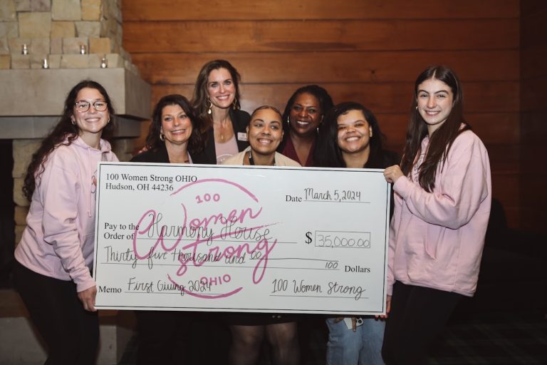 Harmony House volunteers holding large check from 100 Women Strong